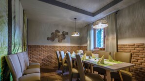 Een eetgedeelte met een bakstenen muur, een tafel met stoelen en een hanglamp.