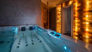 Een moderne spa-ruimte met een jacuzzi, houten wandpanelen en een deur naar een andere kamer.