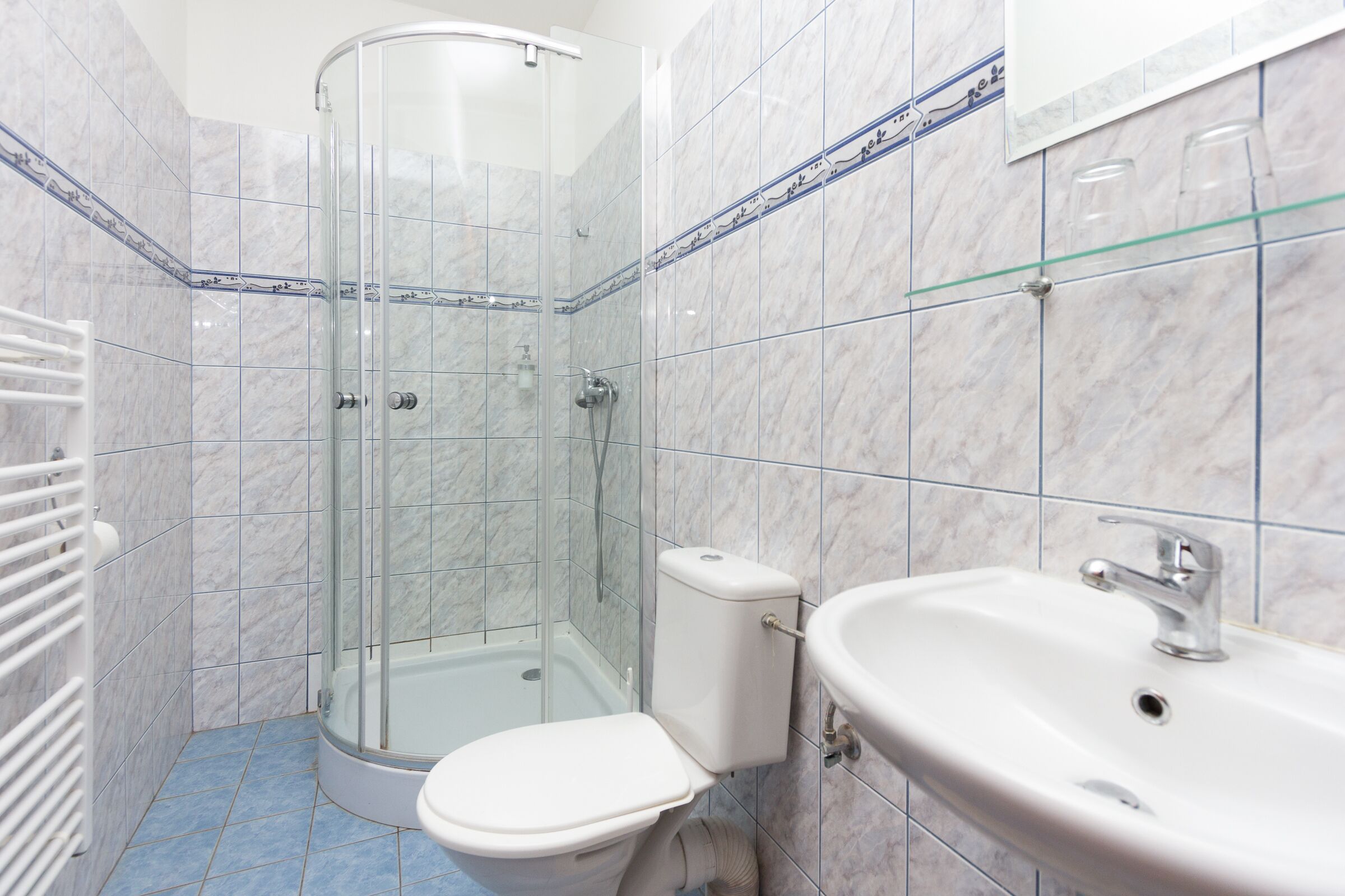 Un baño con ducha envuelta en vidrio, un inodoro y un lavamanos.