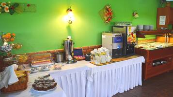 A buffet setup with various food items, a coffee machine, and a beverage dispenser.