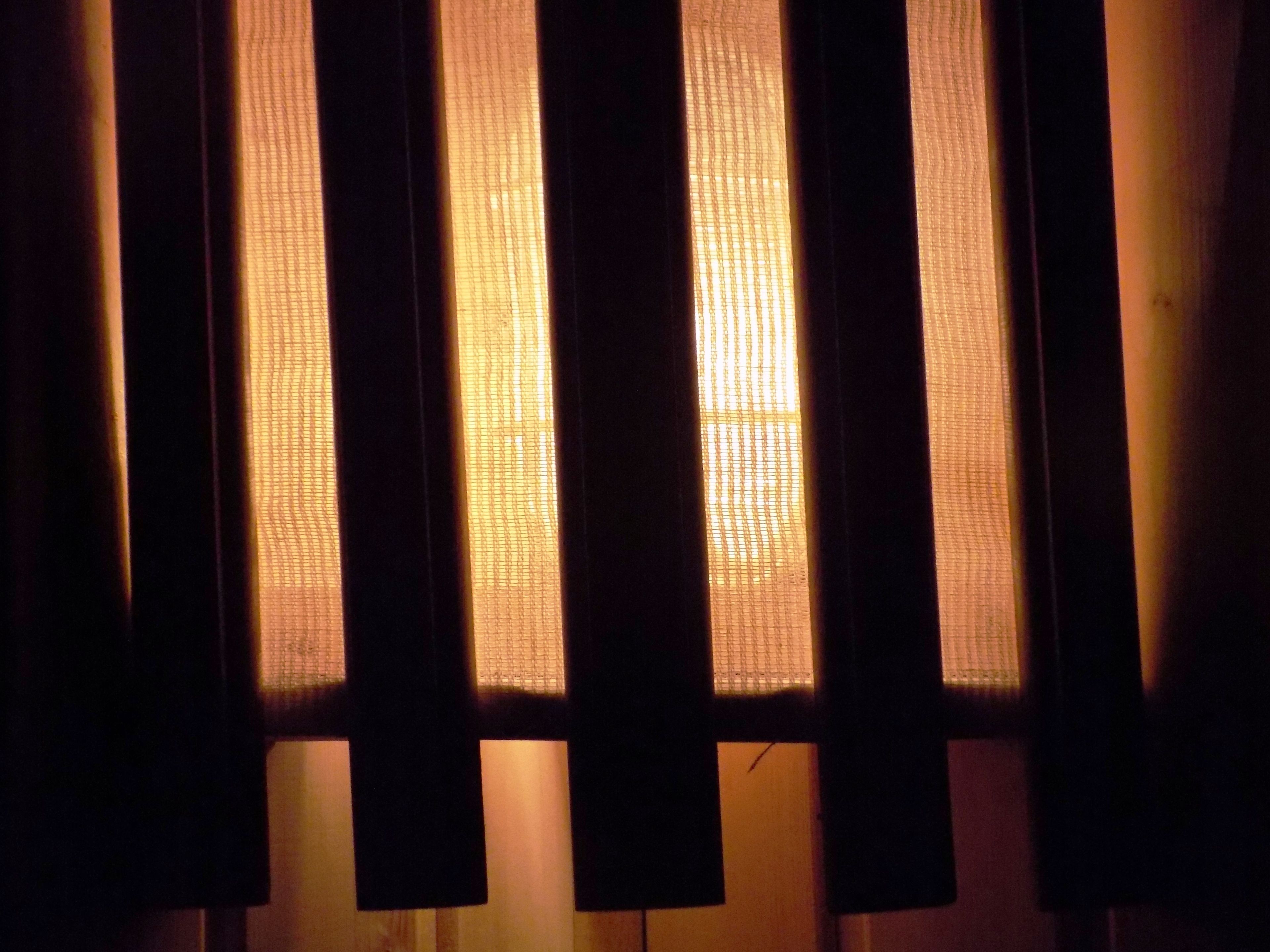 Una ventana con persianas verticales entreabiertas, dejando pasar algo de luz.