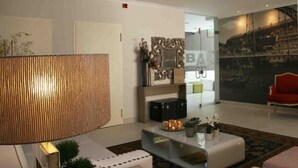 A modern living room with a large, textured wall panel, a glass coffee table with decorative items, and a red sofa. - Hotel Douro Inn (Tabuaço)