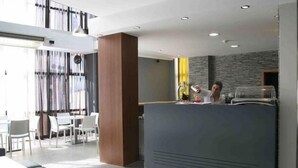A modern reception area with a dark reception desk, white chairs, and a stone wall.