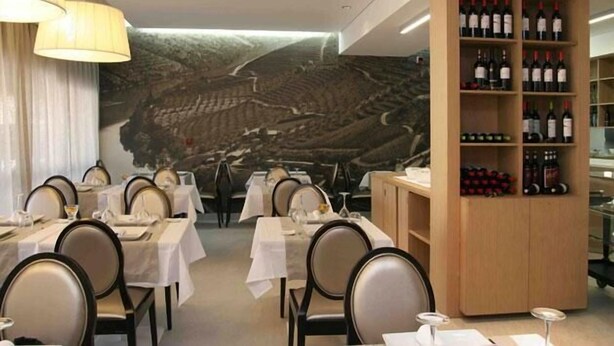 A restaurant with tables set for dining, a wine rack with bottles, and a mural on the wall.