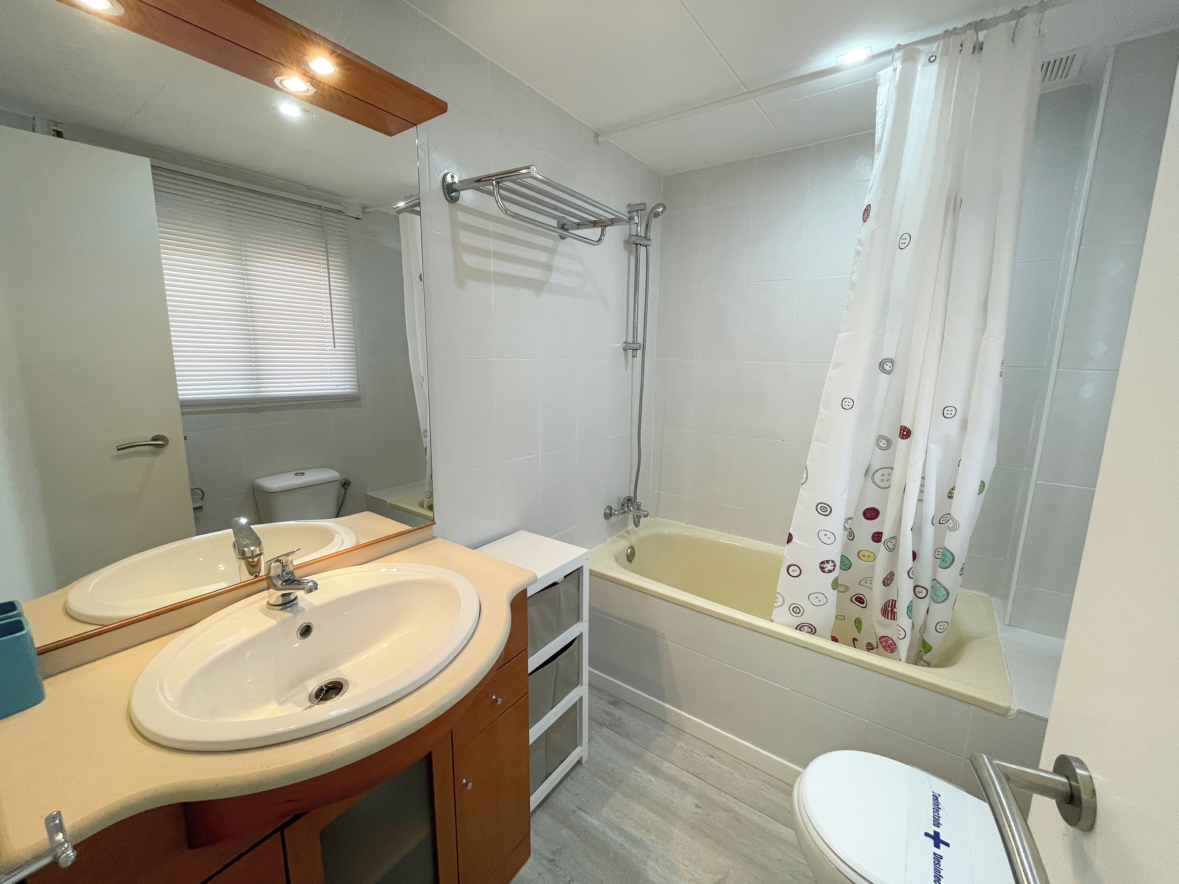 A bathroom with a sink, mirror, toilet, and bathtub.