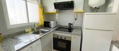 Cocina compacta equipada con lavadora, microondas, cocina y refrigerador.