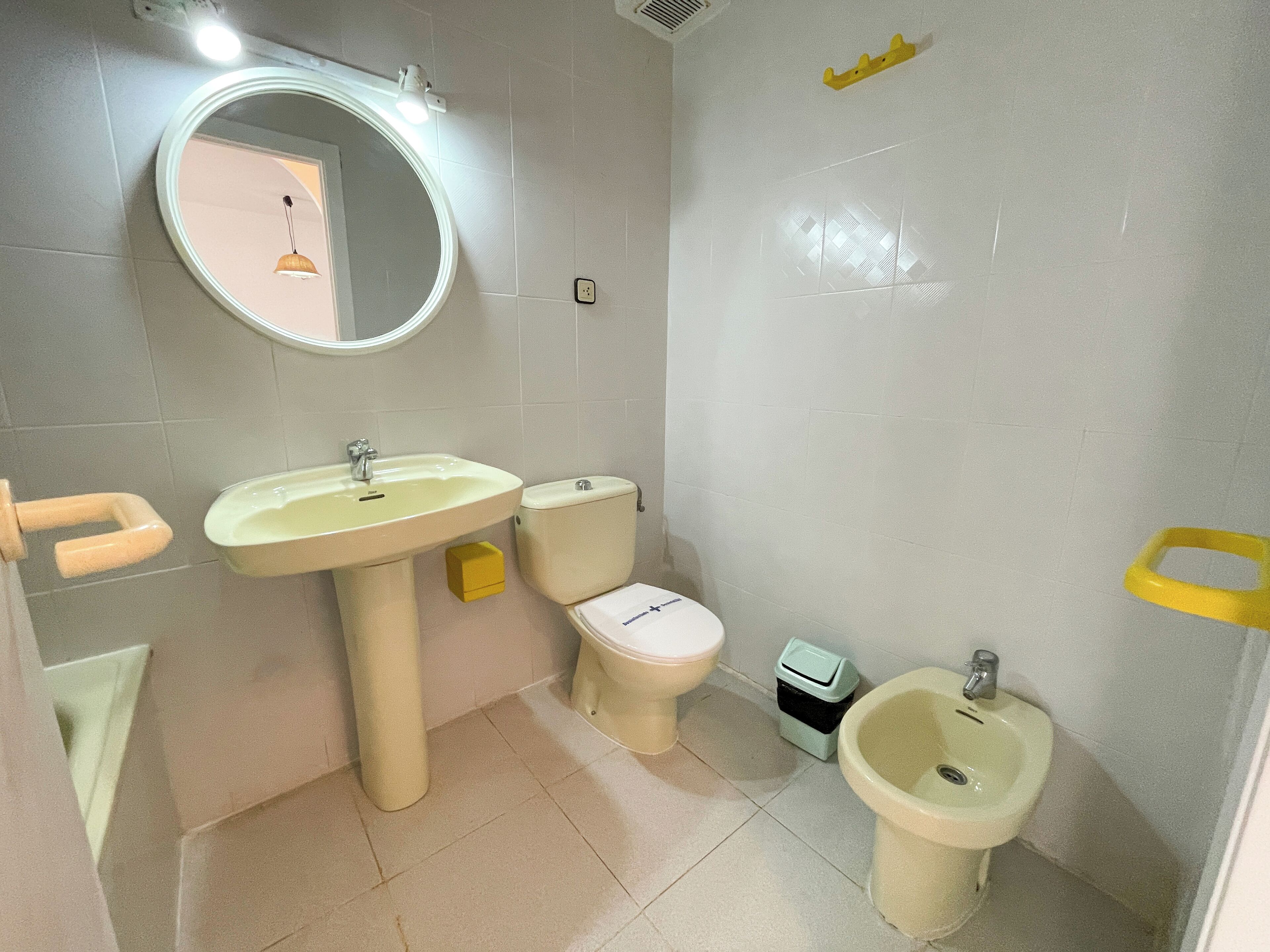 Une salle de bain équipée d’un lavabo, de toilettes, d’un bidet et d ’un miroir.