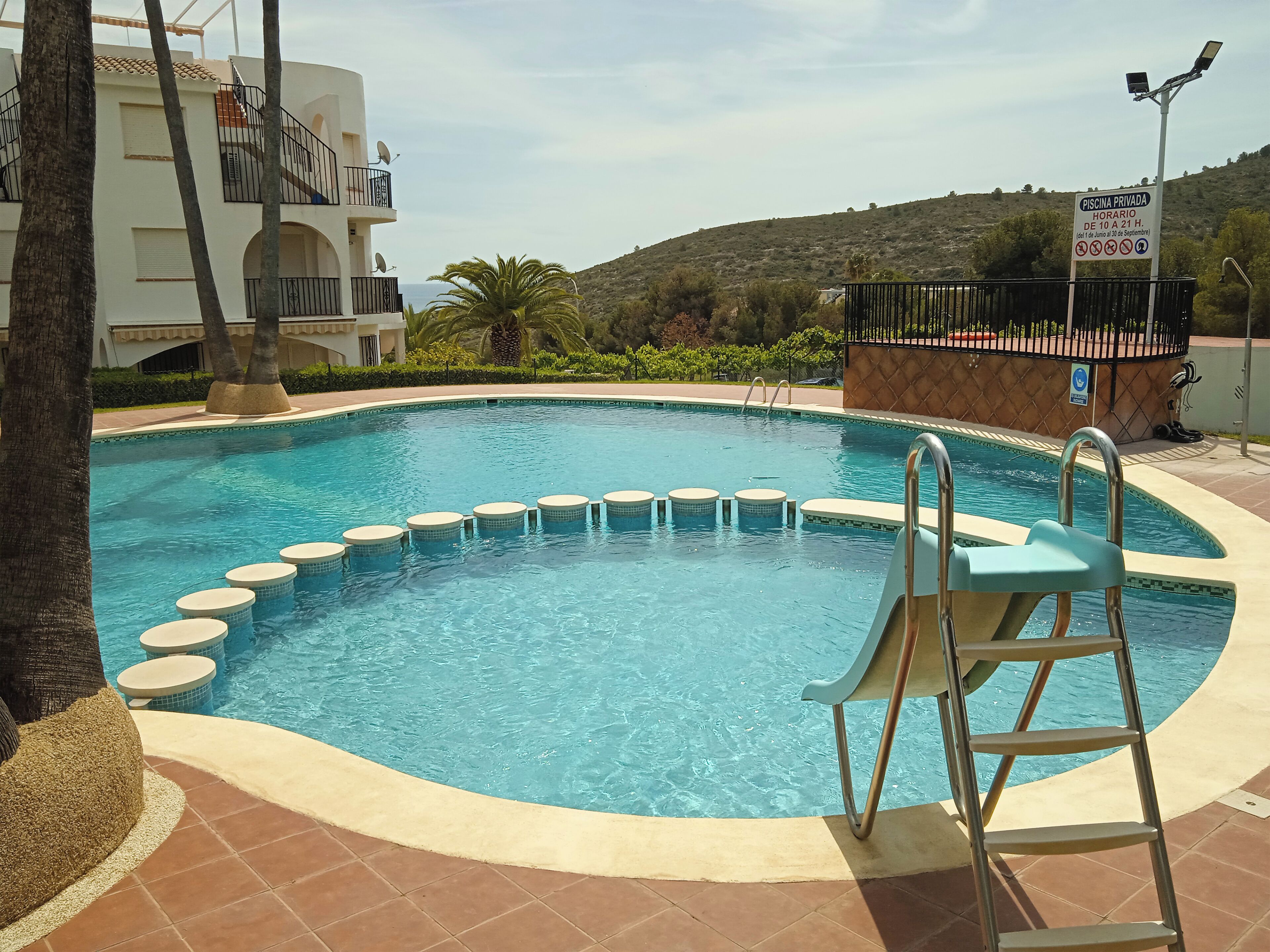 Ein privater Pool mit kreisförmigem Design, einer Leiter und einem Schild, das eingeschränkte Öffnungszeiten anzeigt.