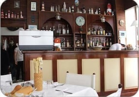 Zona de bar con estantes llenos de botellas y un refrigerador.