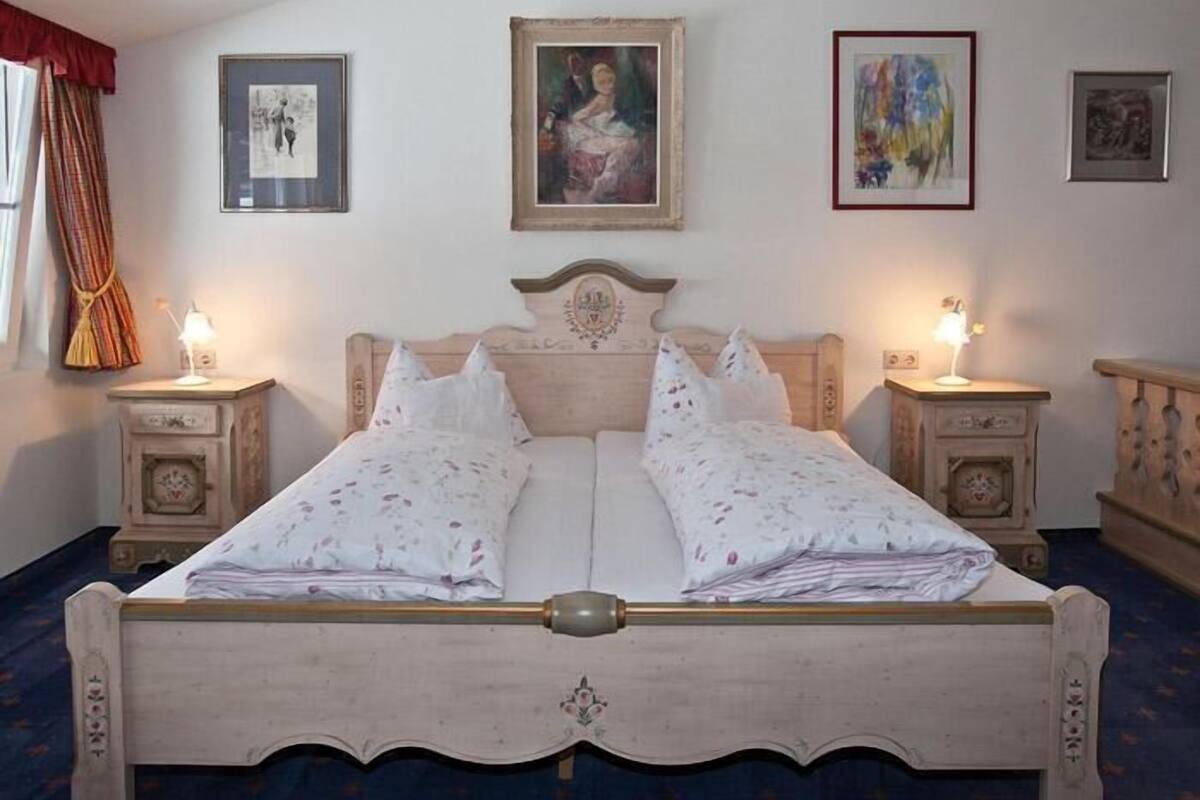 A double bed with a wooden headboard, two bedside tables with lamps, and framed artwork on the walls.
