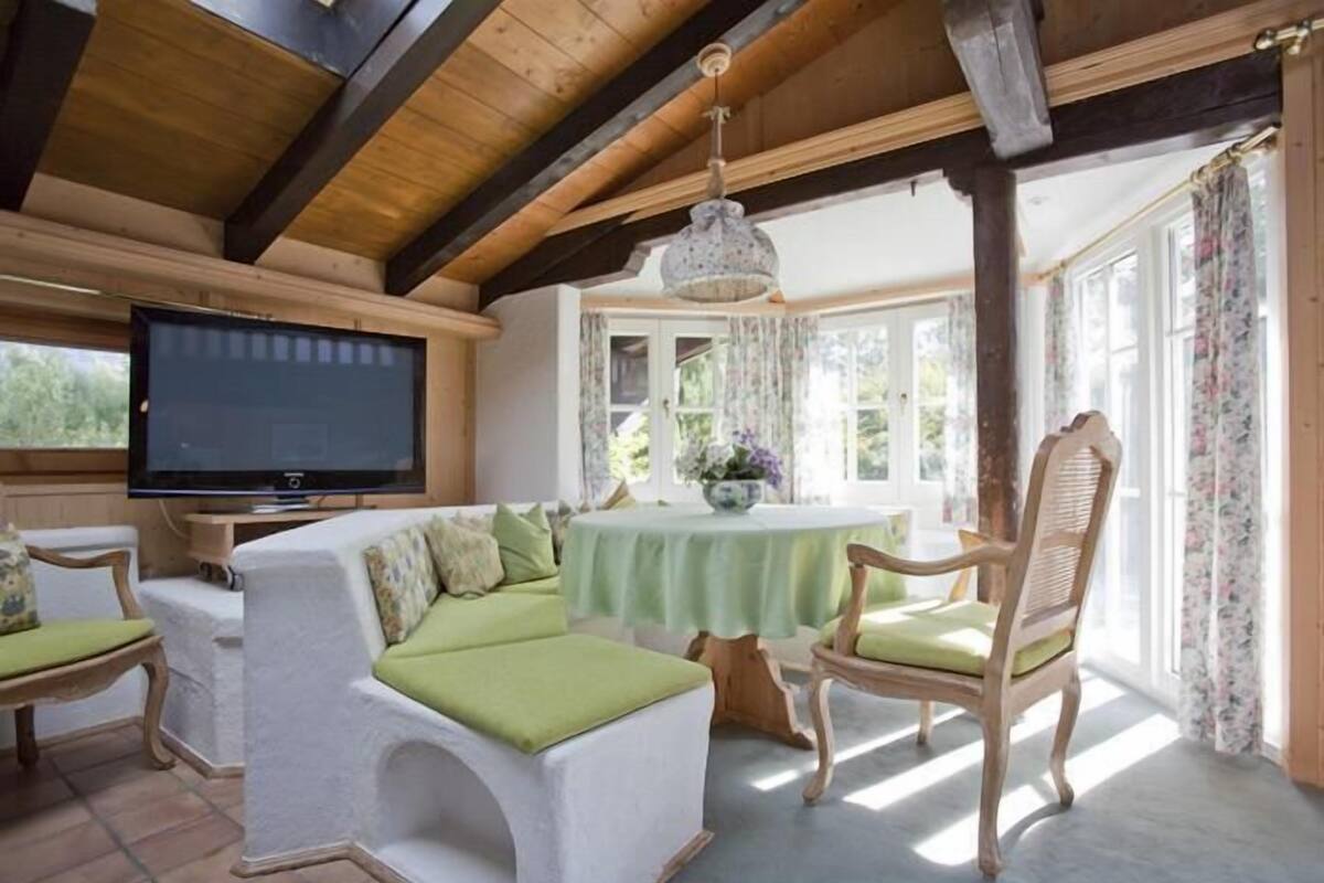 A cozy living room with a television, a sofa, a table, and chairs.