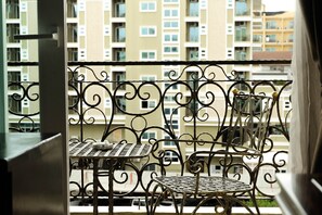 Een balkon met sierhekwerk en twee tafels met stoelen.
