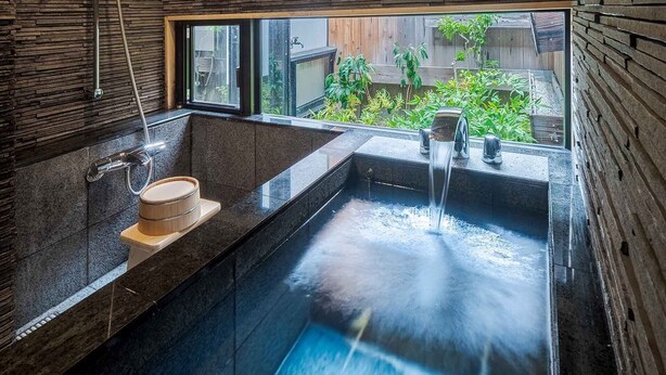A modern bathroom with a large bathtub, a shower, and a window providing a view of the outdoors.