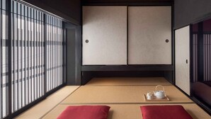 A traditional Japanese room with tatami flooring, sliding doors, and a wooden ceiling.