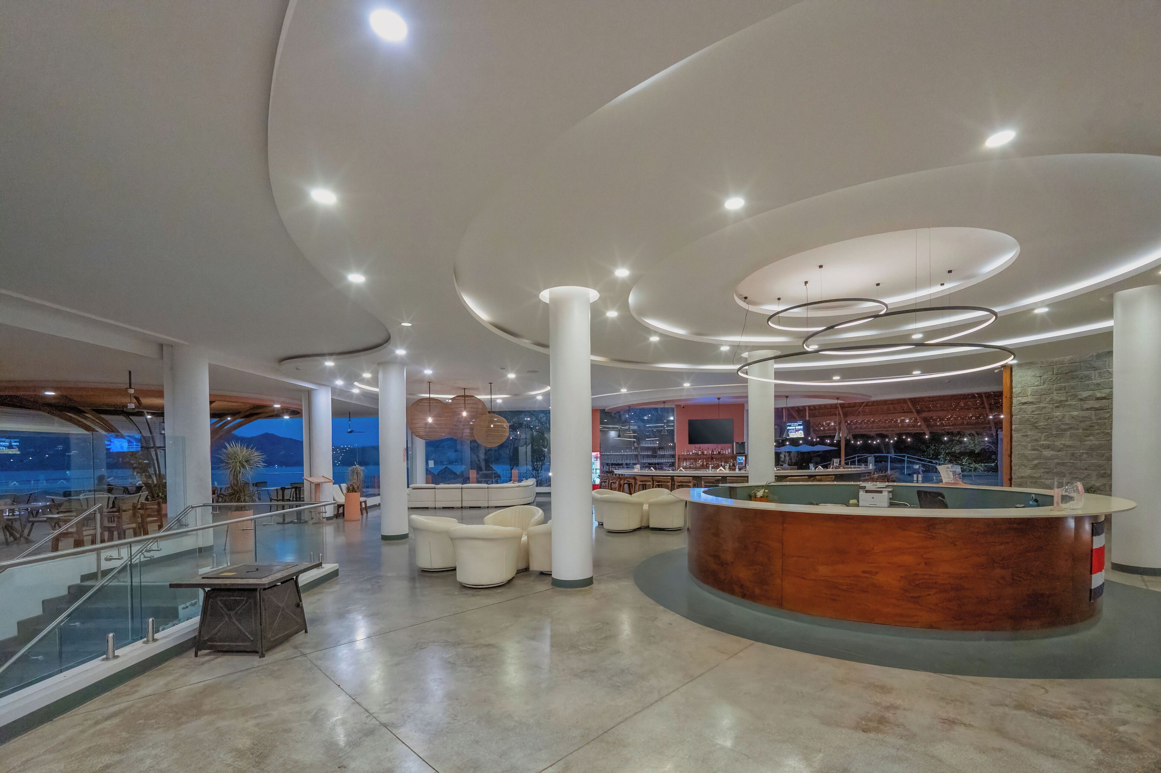 A spacious lobby with a reception desk, seating area, and a view of the cityscape through large windows.