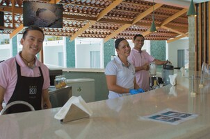 A cafe with a tiled ceiling and a counter where staff are preparing drinks.