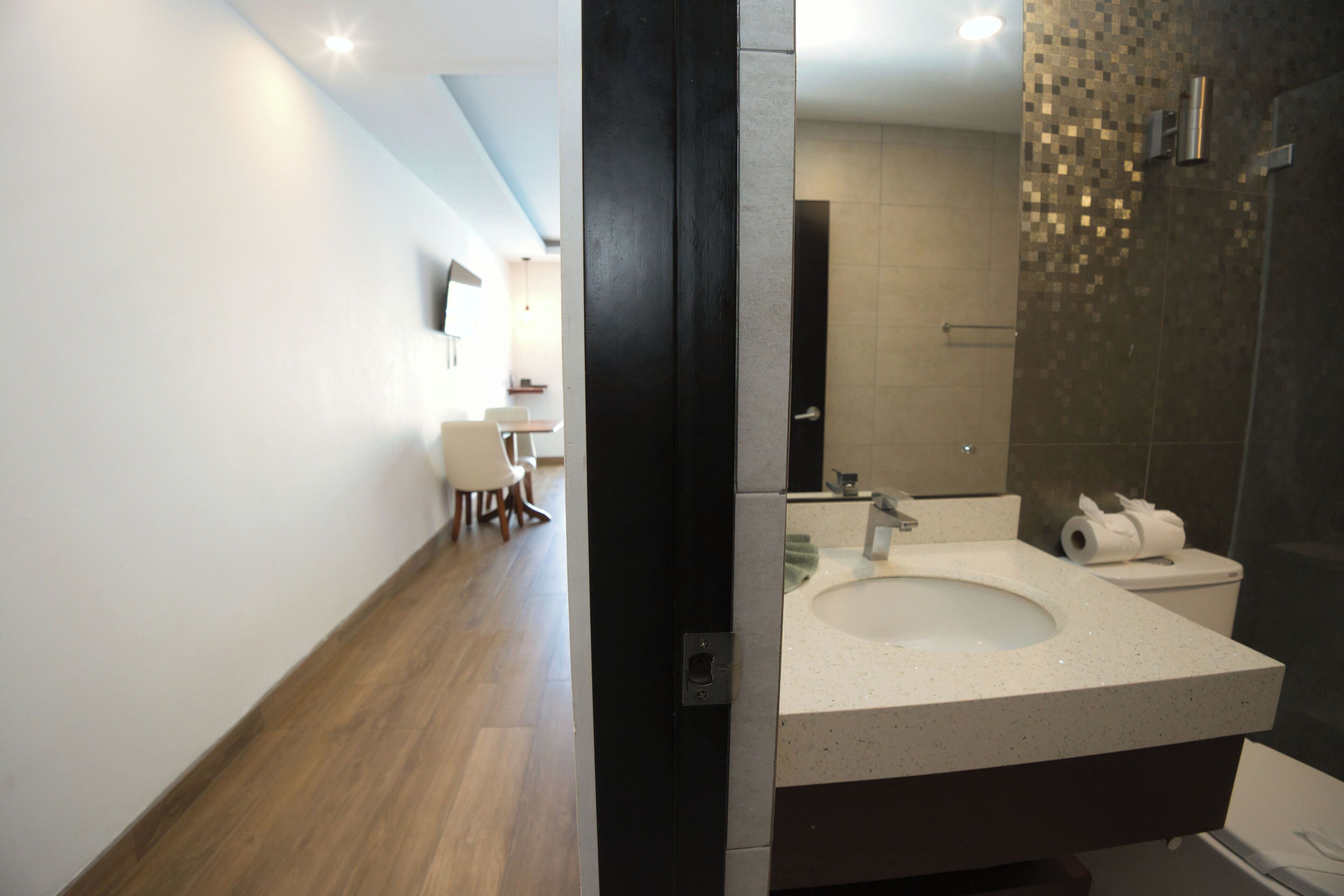 A modern bathroom with a large mirror, a sink, and a toilet.