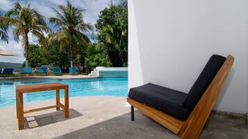 A poolside area with a wooden table and a wooden lounge chair.