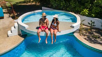 Una piscina al aire libre, sombrillas, sillones reclinables de piscina