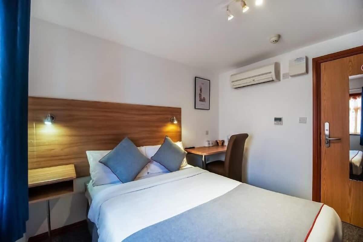 Une chambre d’hôtel comprenant un lit, une table de chevet, un bureau, une chaise et une porte.