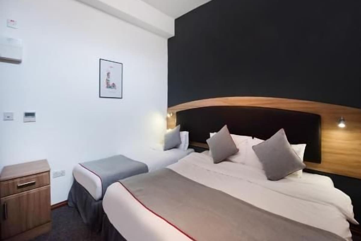 A bedroom with a bed, bedside table, and a wall-mounted light fixture.