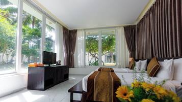 A hotel room with a bed, a TV, a desk, and large windows.