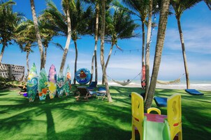 Una playa con palmeras, una hamaca y sillas de playa coloridas.