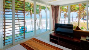 Habitación de hotel con un ventanal que ofrece vistas a la playa y palmeras.