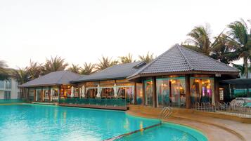 Una piscina al aire libre, sombrillas, sillones reclinables de piscina
