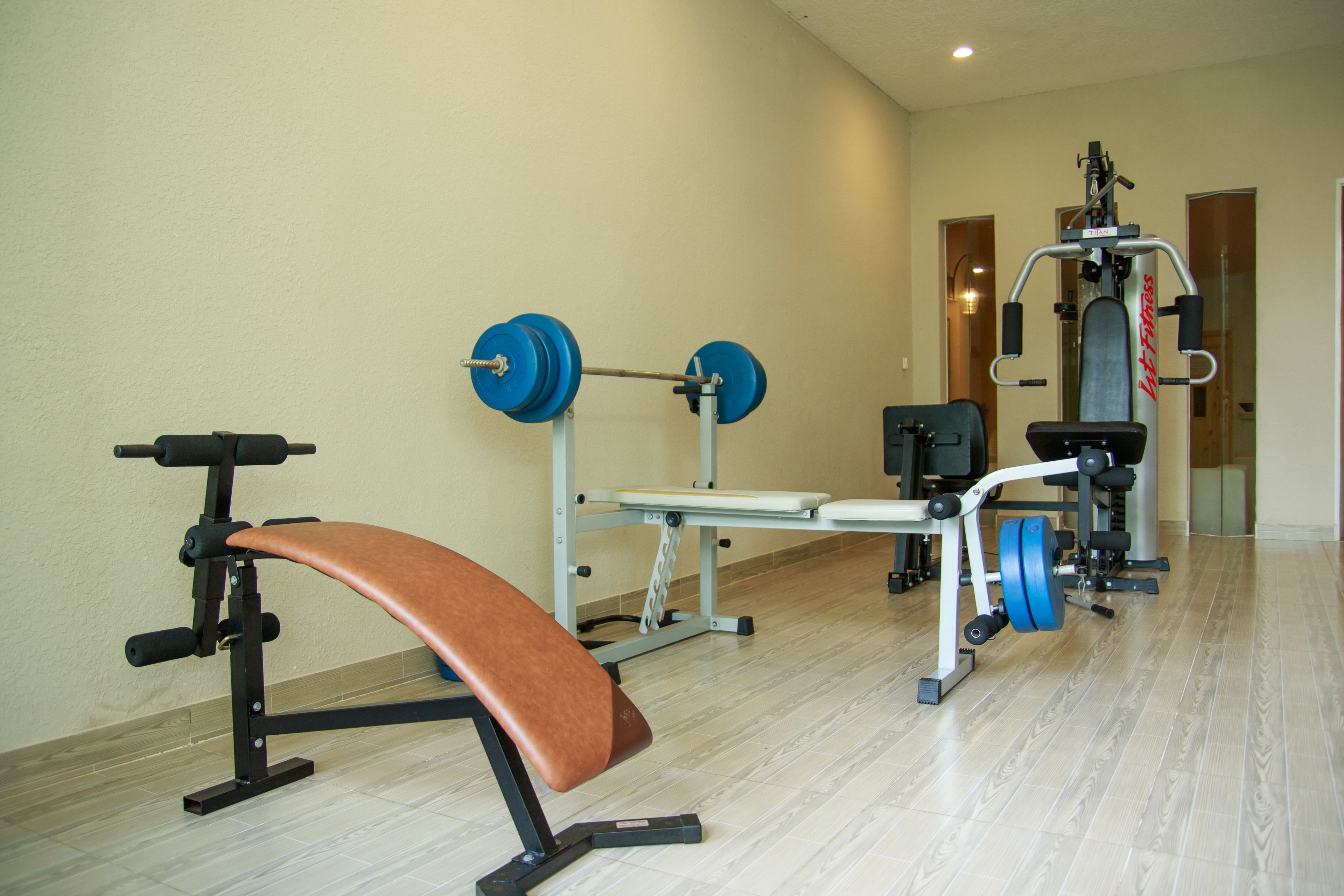 A gym with a bench, weight bench, and various exercise machines.