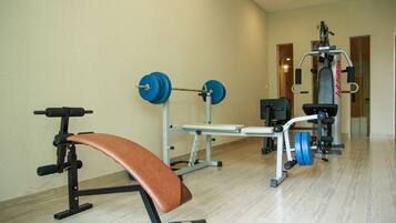 A gym with a bench, weight bench, and various exercise machines.