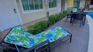 A poolside area with a lounge chair, a table with chairs, and a small pool. - Prism Hotel (Angeles City)
