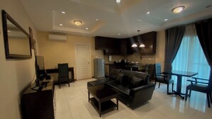 A modern living room with a sofa, coffee table, and a dining area with a table and chairs. - Prism Hotel (Angeles City)