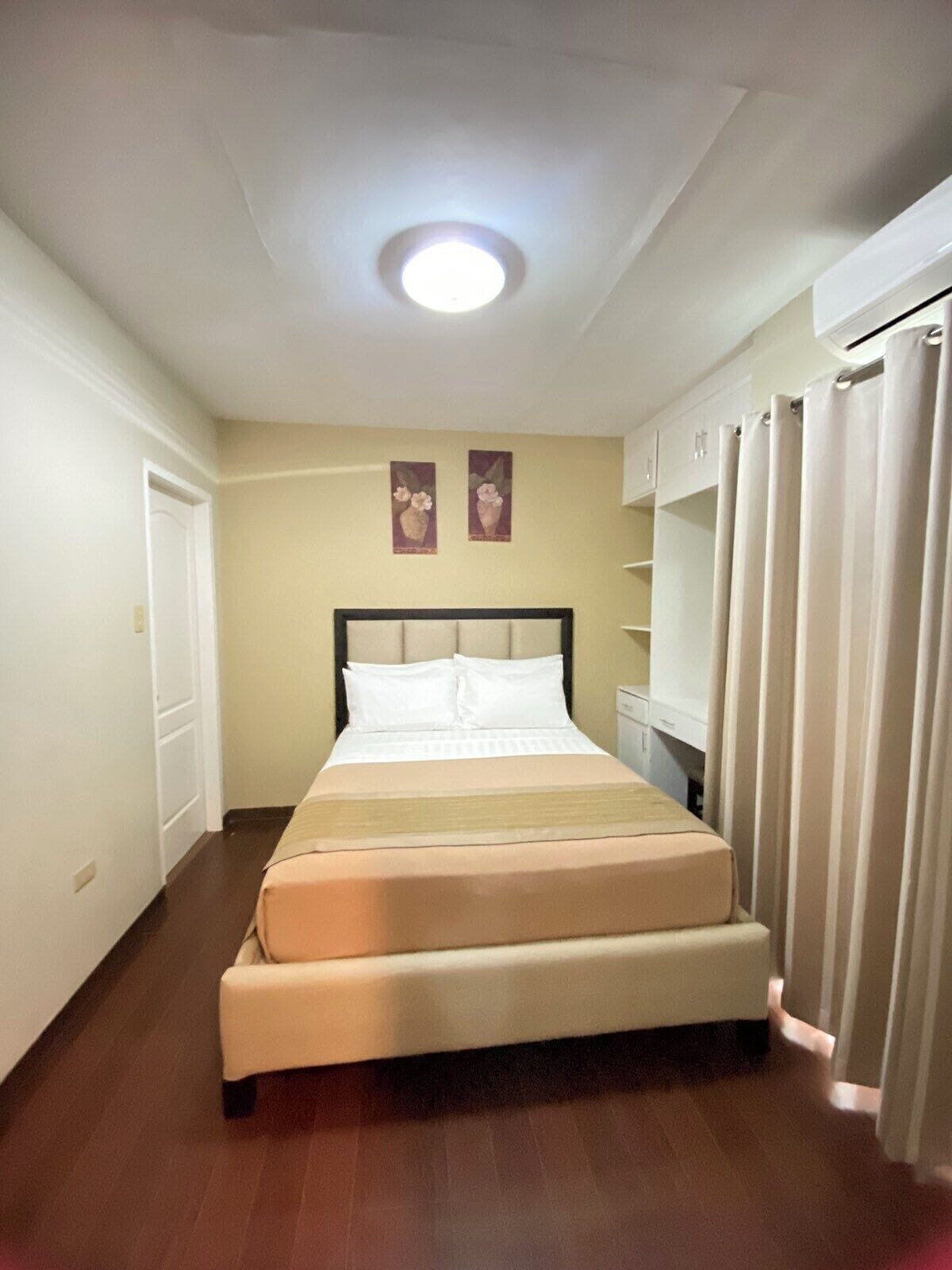 A hotel room with a bed, a wardrobe, and a ceiling light.