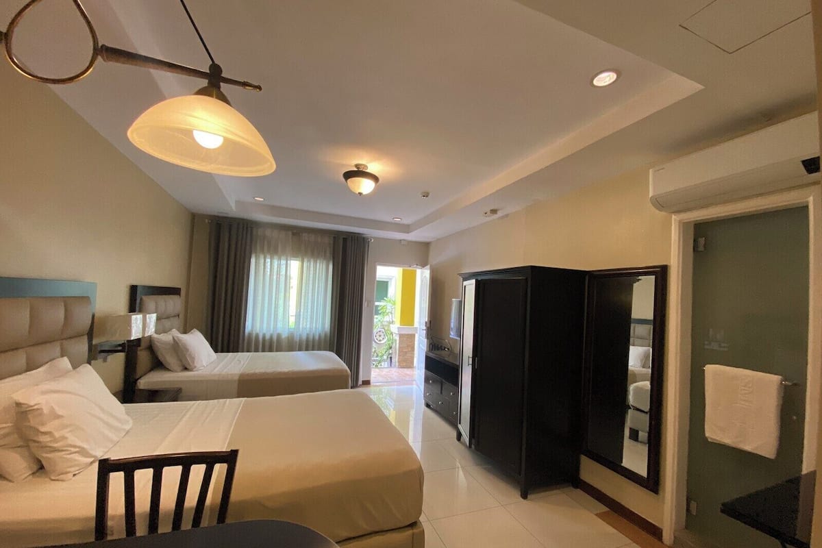 Habitación de hotel con dos camas, un escritorio, un armario y un baño.