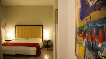 A hotel room with a bed, bedside tables, and a painting on the wall.