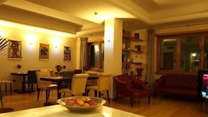 A cozy living room with a dining area, wooden flooring, and a large window. - Hotel Piazza Marconi (Cassino)
