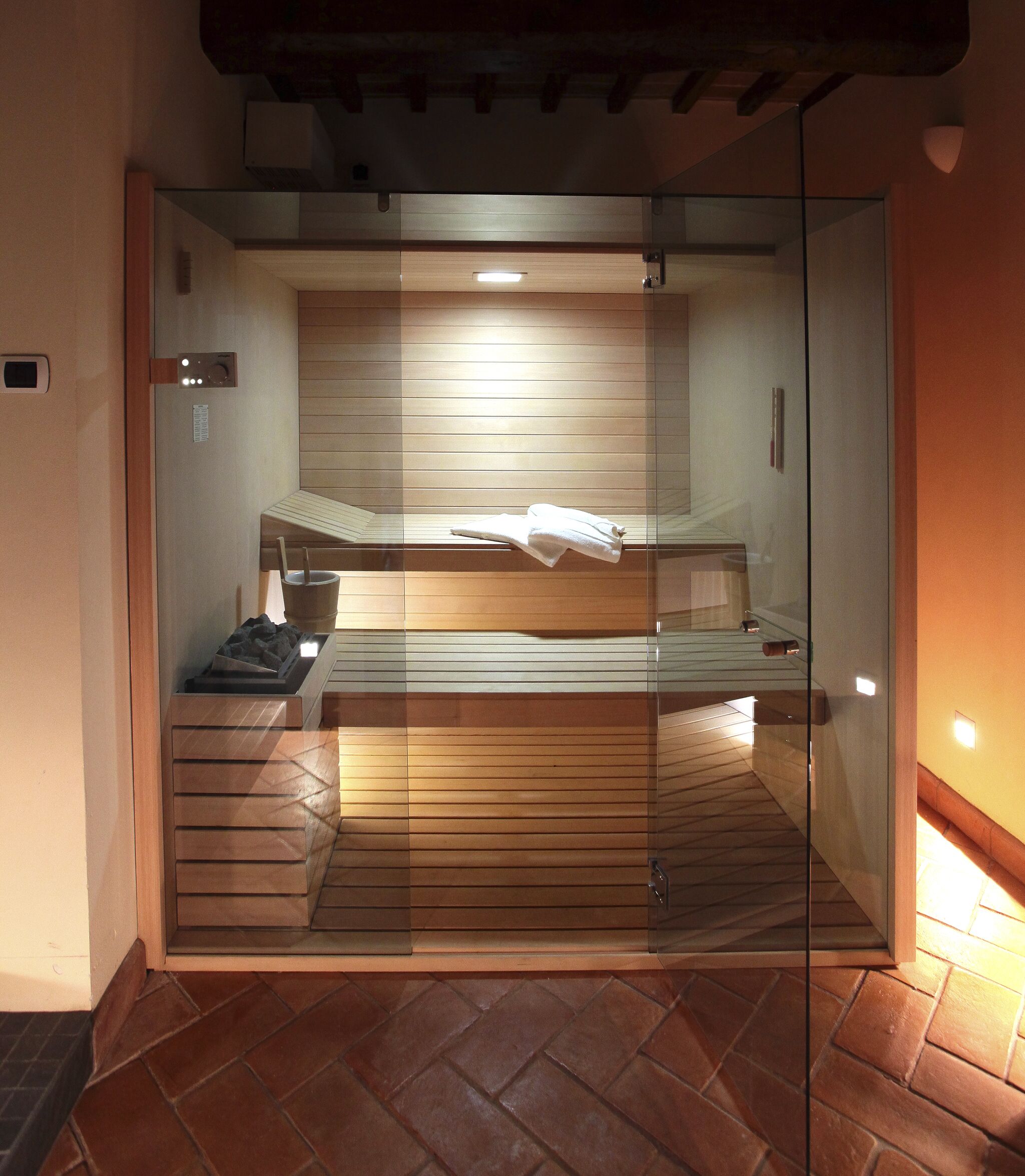 A glass-enclosed sauna with wooden benches and a towel rack.