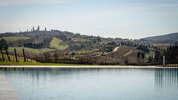 Une piscine offrant une vue sur un paysage vallonné, avec des vignobles et, au loin, le profil d’une ville.