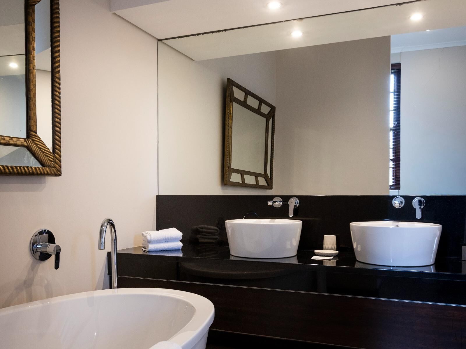 Une salle de bain moderne avec une baignoire sur pieds, deux lavabos et un grand miroir.