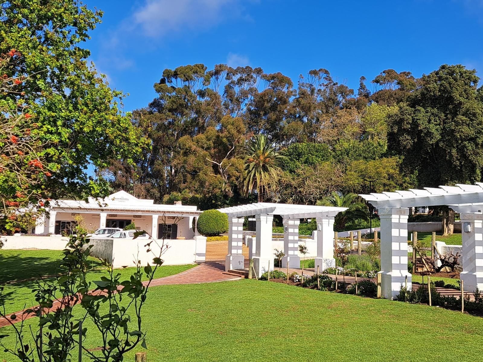 A hotel with a covered outdoor area, a well-maintained lawn, and a variety of trees in the background.