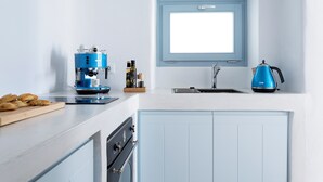 A kitchen with a blue coffee maker, a kettle, and a cutting board with pastries. - Helestia Pocket Hotel, Caldera Santorini (Santorini)