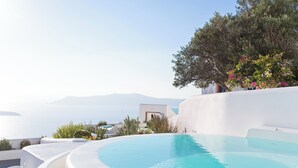 A pool with a curved edge, surrounded by white walls and greenery, overlooking a body of water and distant mountains. - Helestia Pocket Hotel, Caldera Santorini (Santorini)