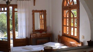 A room with a bed, a wooden desk, a mirror, and a window with a wooden frame. - Pantheon Studios Apartments (Thasos)
