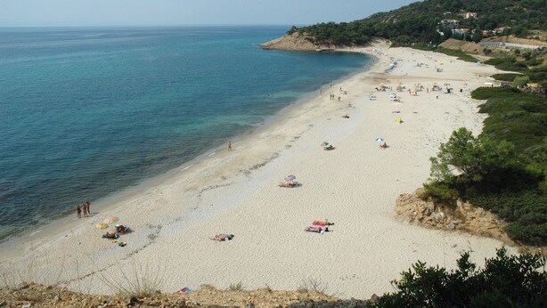 A beach with clear blue water, sandy shore, and a few umbrellas. - Pantheon Studios Apartments (Thasos)