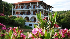 A multi-story building with balconies, surrounded by lush greenery and flowering plants. - Pantheon Studios Apartments (Thasos)