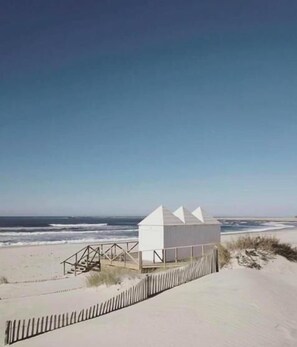 Une maison de plage au design simple et moderne, dotée d’un toit plat et d’un petit espace porche.