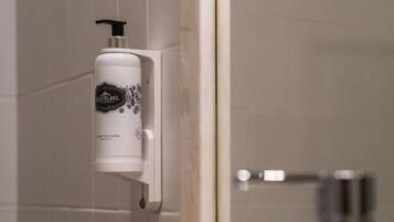 A bathroom with a hand soap dispenser mounted on the wall, a mirror, and a sink with a faucet.