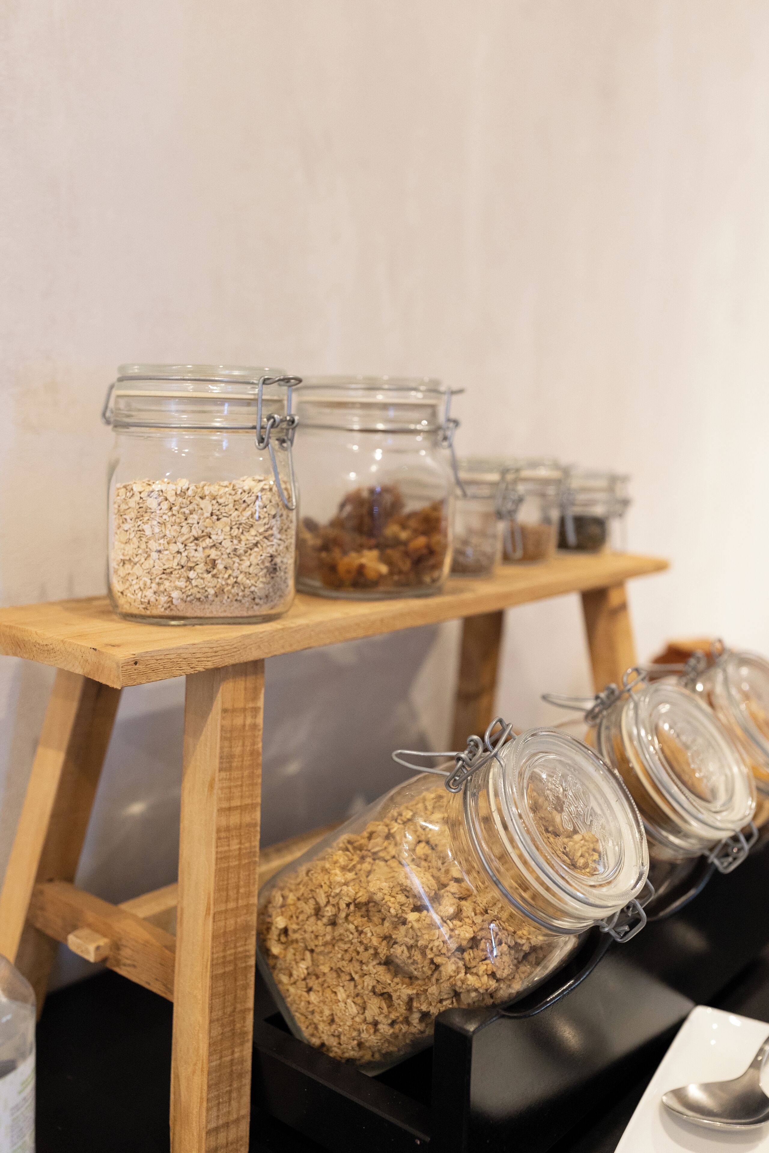Una estantería de madera con varios frascos de vidrio que contienen diferentes alimentos.