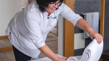 Hotel staff member folding a towel in a guest room with a simple design.
